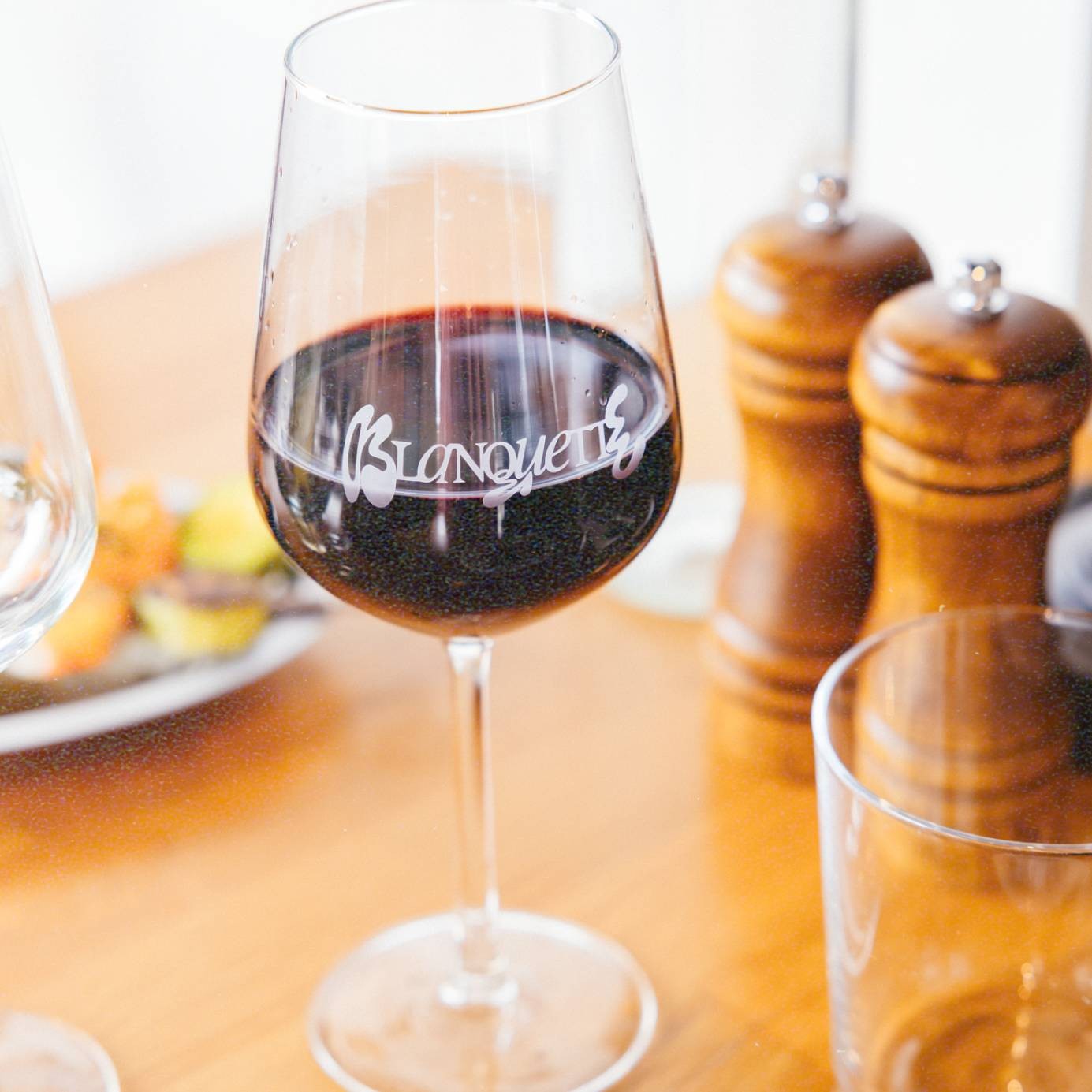 Verre de vin rouge gravé du logo Blanquette posé sur la table