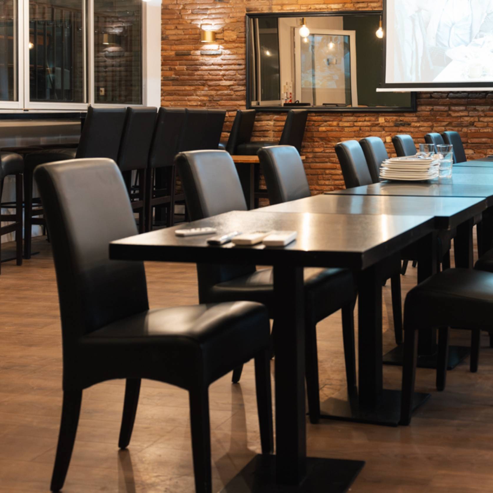 Salle privatisable du restaurant Blanquette à Toulouse, longue table en bois sombre, mur de briques